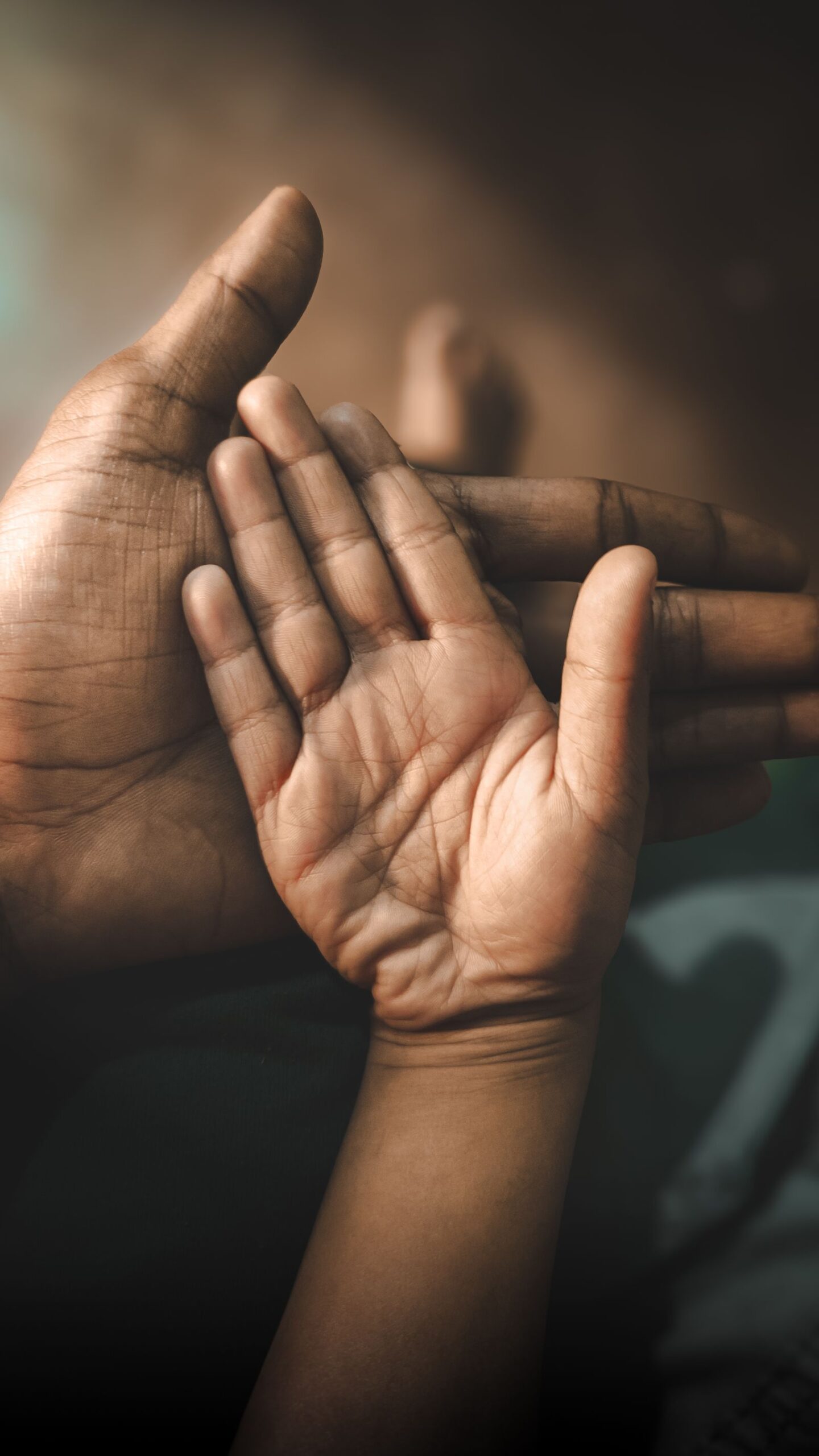 Die geöffnete Hand eines Erwachsenen und die kleinere Hand eines Kindes berühren sich